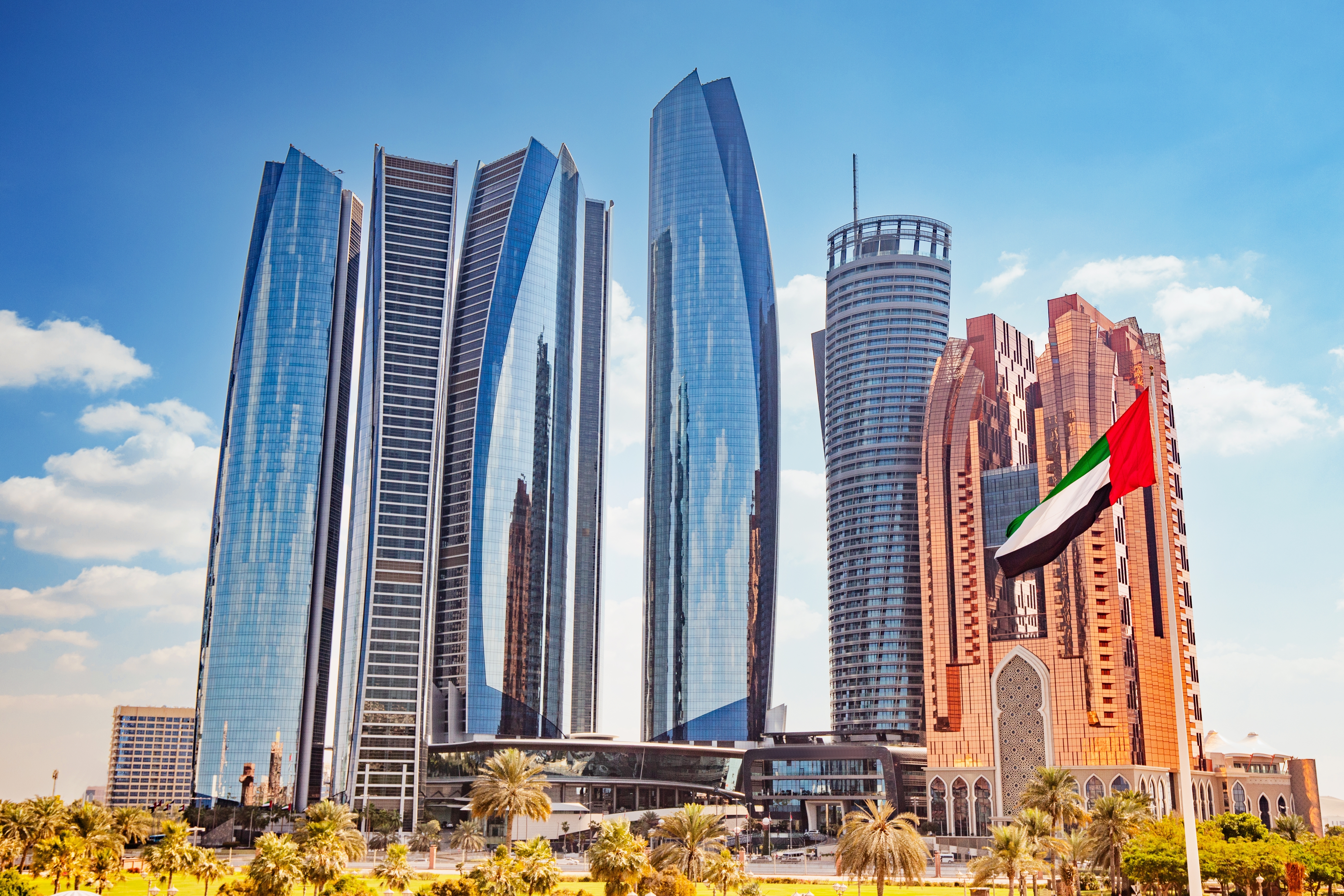 The UAE flag flutters in the breeze against a backdrop of modern skyscrapers in Abu Dhabi